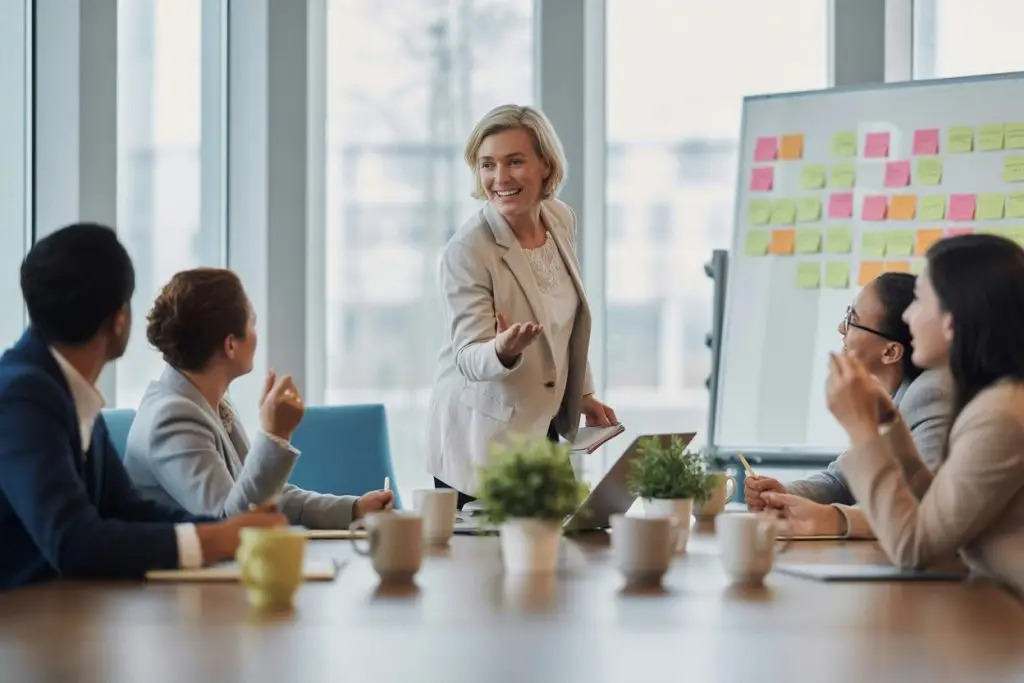 confident facilitator (mid-30s–50s) leading a corporate training workshop in a modern meeting room